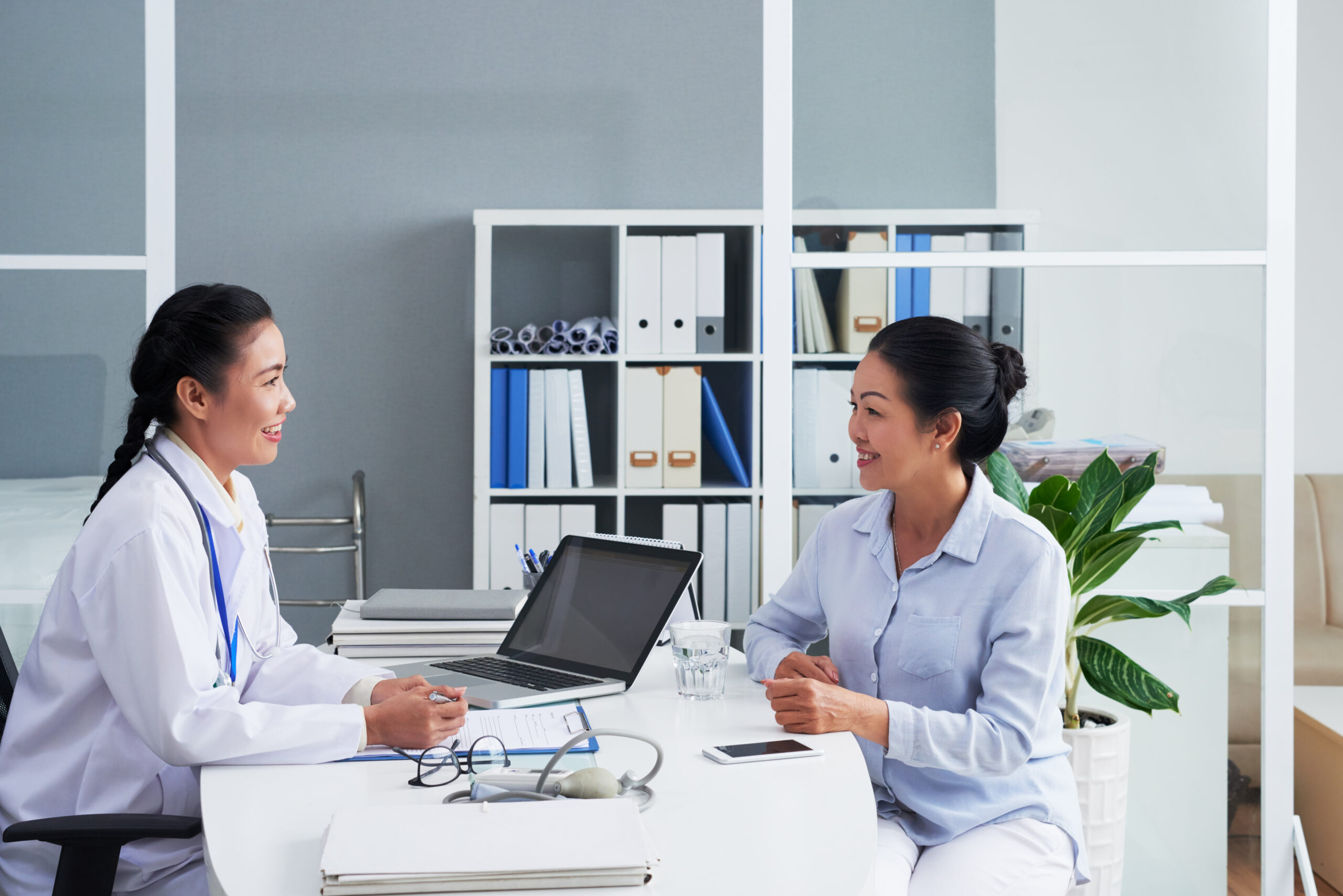 Smiling Asian doctor consulting senior female patient